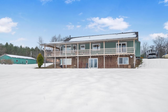 snow covered back of property featuring a balcony