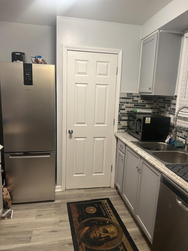 kitchen featuring appliances with stainless steel finishes, tasteful backsplash, light hardwood / wood-style floors, sink, and gray cabinets