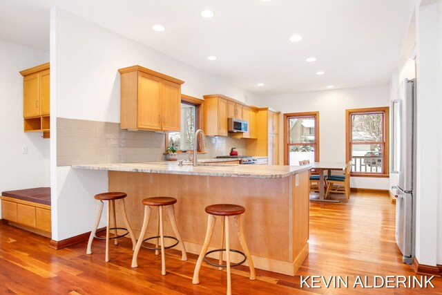 kitchen featuring kitchen peninsula, sink, appliances with stainless steel finishes, and light wood-type flooring