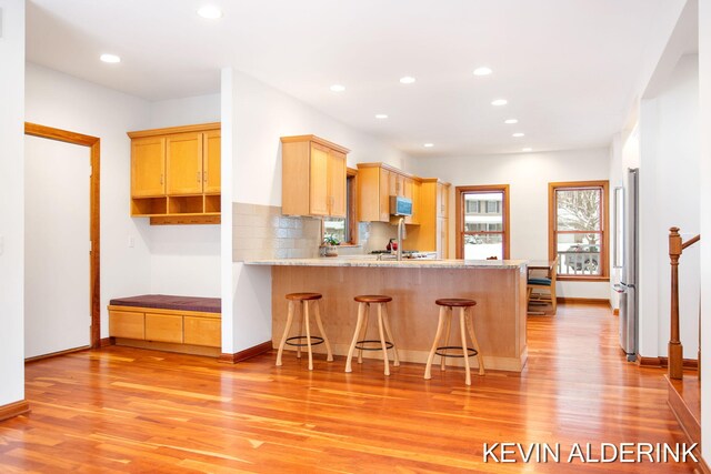 kitchen featuring kitchen peninsula, a kitchen breakfast bar, light wood-type flooring, and stainless steel appliances