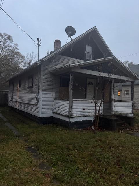 view of side of home with a yard and covered porch