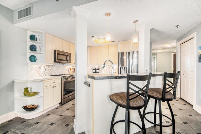 kitchen featuring hanging light fixtures, stainless steel appliances, a kitchen breakfast bar, backsplash, and a textured ceiling