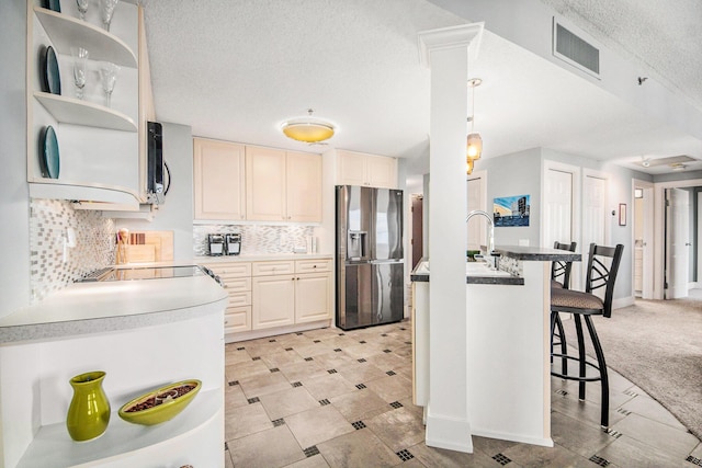 kitchen with a kitchen bar, backsplash, a textured ceiling, pendant lighting, and stainless steel fridge with ice dispenser