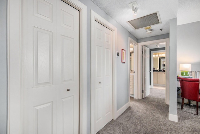 hallway featuring light carpet and a textured ceiling