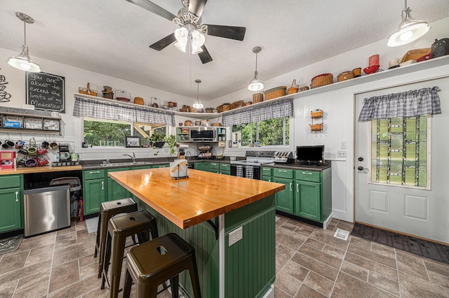 kitchen with a breakfast bar, green cabinetry, wooden counters, a center island, and electric range oven