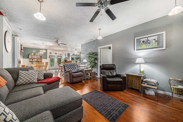 living room with dark hardwood / wood-style flooring, ceiling fan with notable chandelier, and a textured ceiling