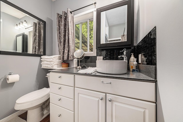 bathroom featuring vanity, decorative backsplash, and toilet