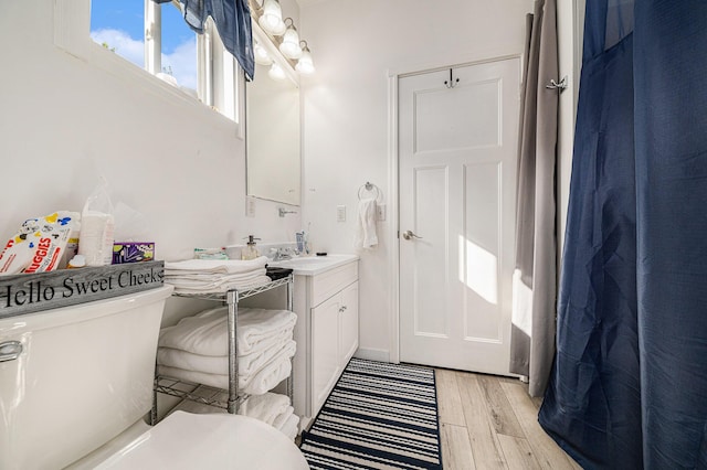 bathroom with wood-type flooring, toilet, and vanity