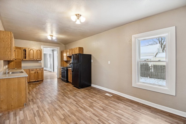 kitchen with a textured ceiling, sink, light hardwood / wood-style floors, and black appliances