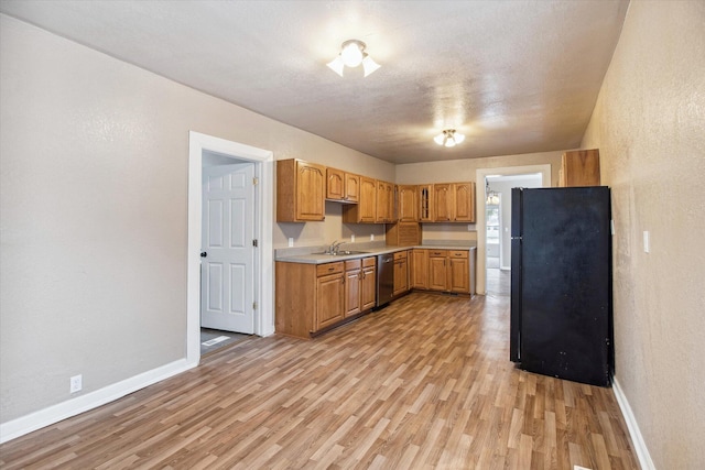 kitchen featuring black refrigerator, sink, stainless steel dishwasher, light wood-type flooring, and a textured ceiling