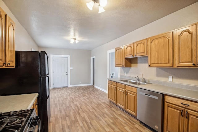 kitchen featuring a textured ceiling, dishwasher, light wood-type flooring, and sink