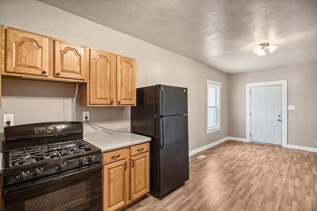 kitchen with black appliances, light wood-type flooring, and a textured ceiling