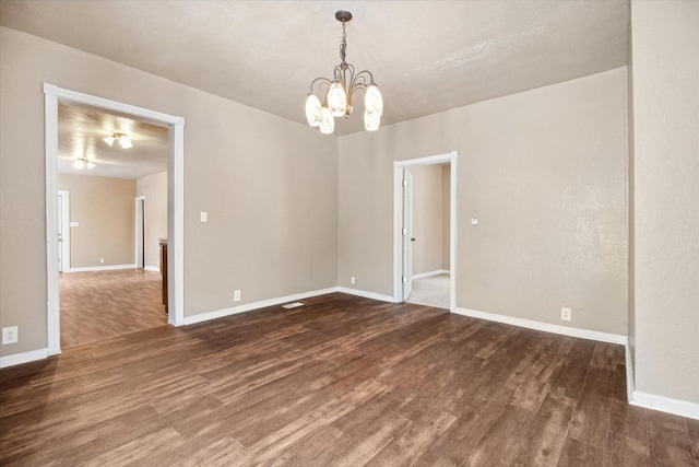 unfurnished room with a chandelier and dark hardwood / wood-style floors