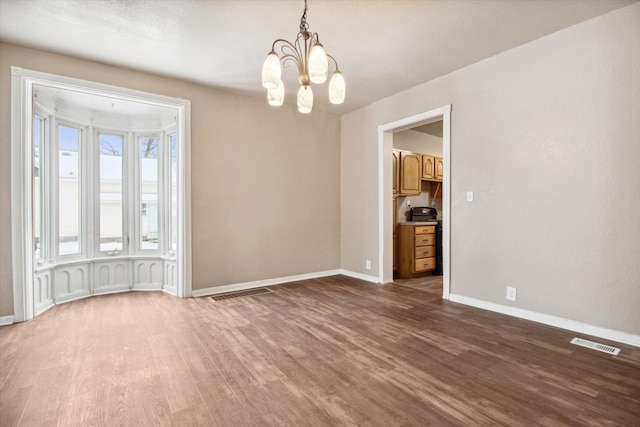 unfurnished room featuring dark hardwood / wood-style flooring and an inviting chandelier