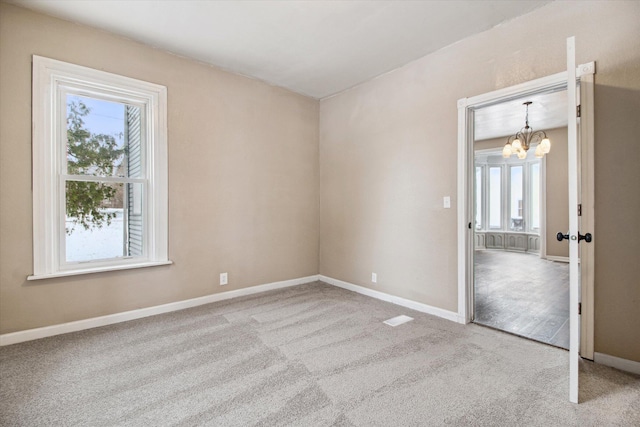 carpeted empty room featuring a chandelier