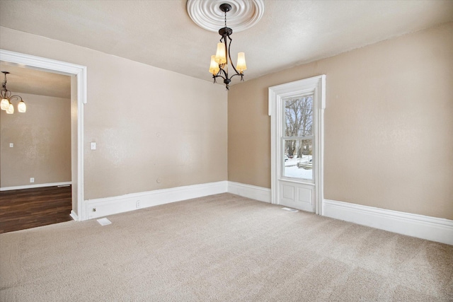 carpeted empty room featuring a notable chandelier