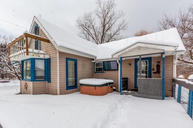 snow covered house with a balcony and a hot tub