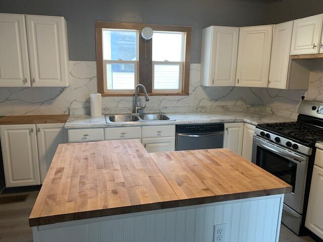 kitchen featuring wooden counters, appliances with stainless steel finishes, white cabinets, and sink