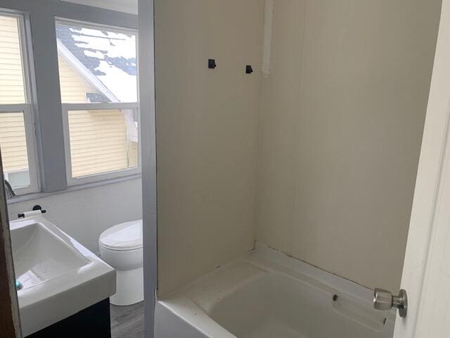 bathroom featuring a tub, vanity, and toilet