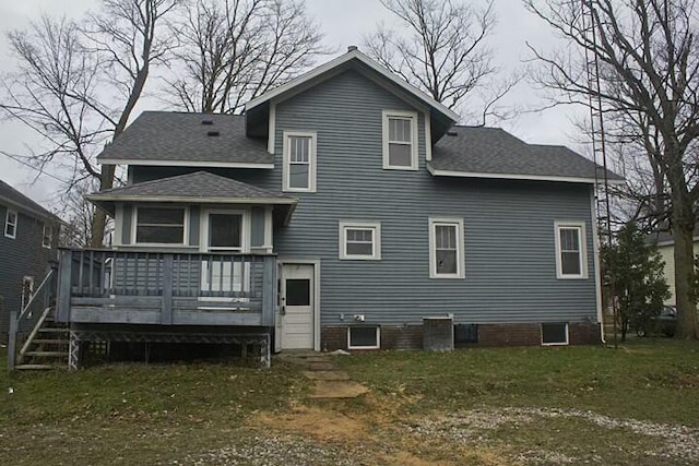 rear view of property featuring a wooden deck and a lawn