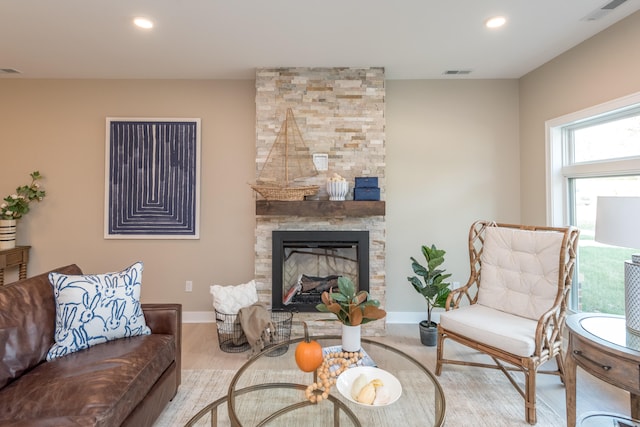 living room featuring a stone fireplace and light hardwood / wood-style floors