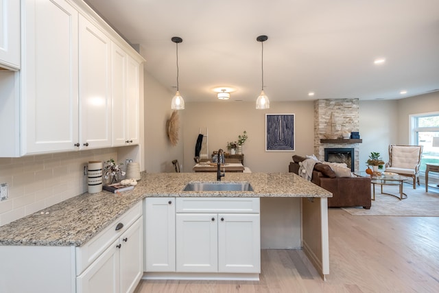 kitchen with white cabinets, light hardwood / wood-style floors, kitchen peninsula, and sink