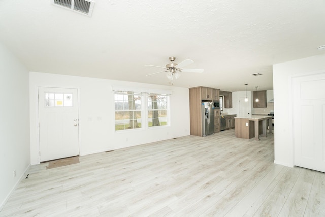 unfurnished living room with ceiling fan, a textured ceiling, and light wood-type flooring