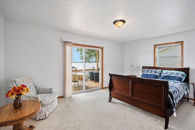 bedroom with a textured ceiling, light carpet, and access to outside