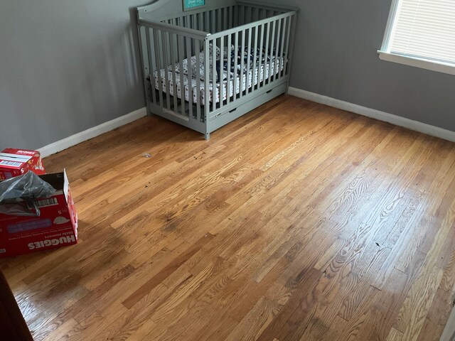 unfurnished bedroom featuring wood-type flooring and a nursery area