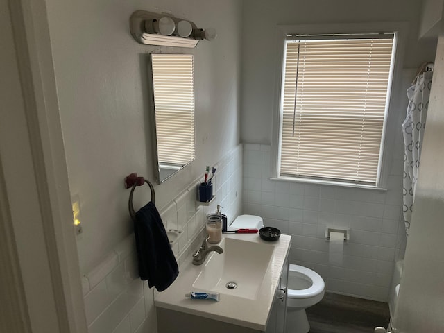 bathroom featuring a shower with curtain, wood-type flooring, toilet, vanity, and tile walls