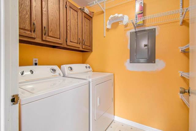 clothes washing area featuring washer and clothes dryer, cabinets, and electric panel