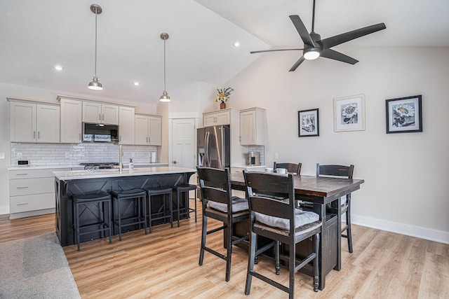 dining room featuring ceiling fan, light hardwood / wood-style floors, and vaulted ceiling