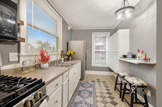 kitchen with a wealth of natural light, sink, white cabinets, and appliances with stainless steel finishes