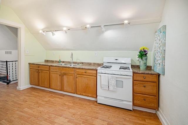 kitchen featuring track lighting, sink, white gas range oven, vaulted ceiling, and light hardwood / wood-style floors