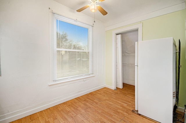 unfurnished bedroom featuring a closet, white refrigerator, light hardwood / wood-style floors, and ceiling fan