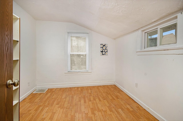 additional living space with light hardwood / wood-style floors and lofted ceiling