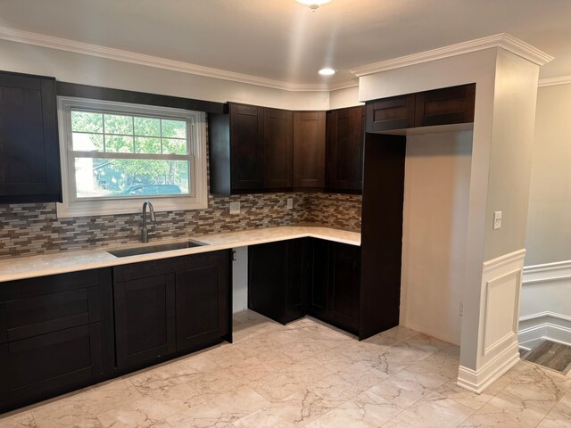 kitchen featuring tasteful backsplash, dark brown cabinetry, sink, and ornamental molding