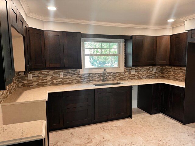 kitchen with tasteful backsplash, dark brown cabinetry, sink, and ornamental molding