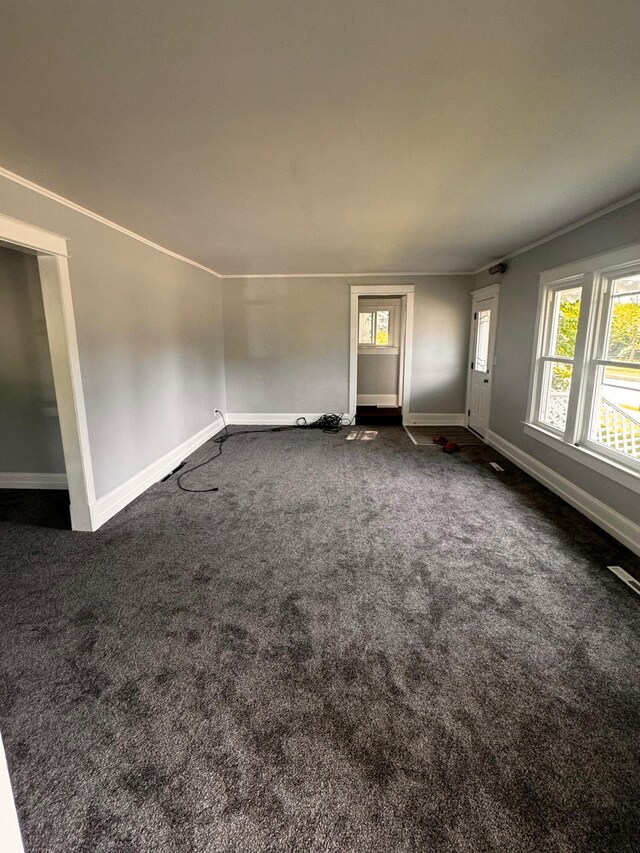 unfurnished living room featuring dark colored carpet and crown molding