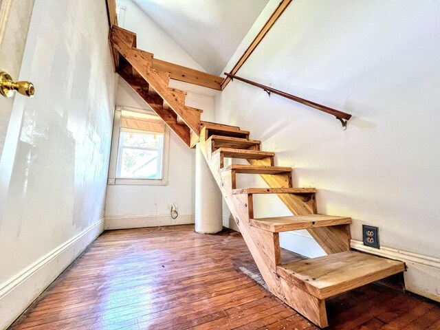 stairway with wood-type flooring and vaulted ceiling