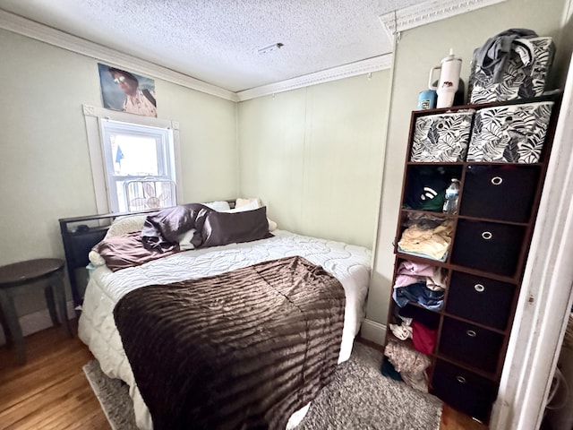 bedroom featuring hardwood / wood-style floors, a textured ceiling, and crown molding