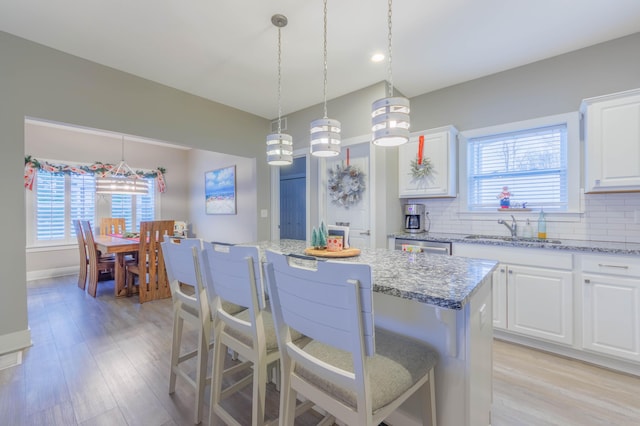 kitchen featuring a breakfast bar, a center island, white cabinetry, and sink