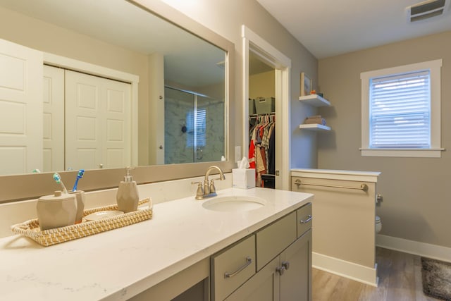 bathroom with hardwood / wood-style floors, vanity, toilet, and a shower with shower door