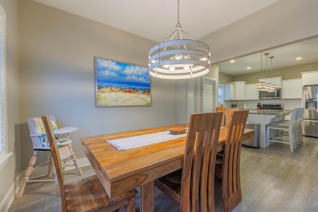 dining space with light hardwood / wood-style floors and a notable chandelier