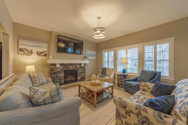 living room with a fireplace, light hardwood / wood-style flooring, and an inviting chandelier