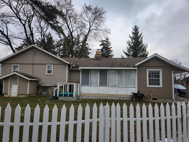 view of front of house with roof with shingles, a fenced front yard, and a chimney