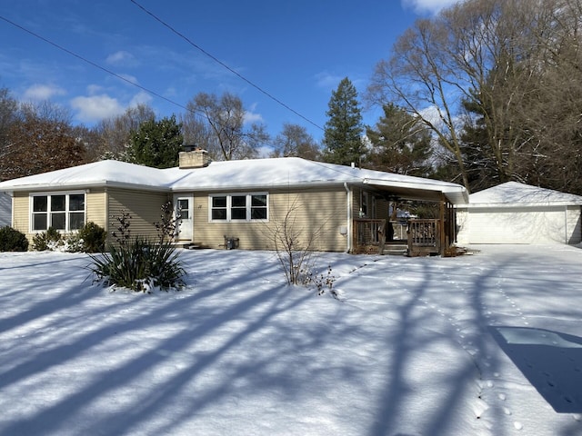 snow covered property with a garage and an outbuilding