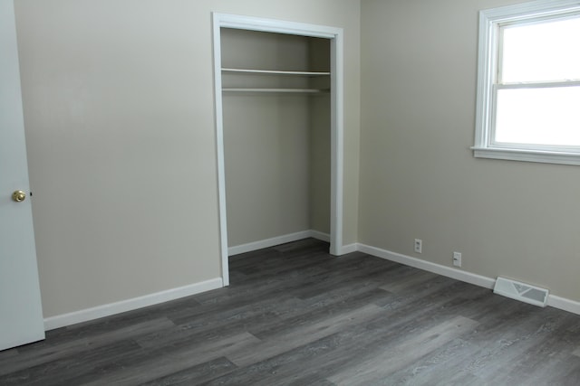 unfurnished bedroom featuring dark wood-type flooring and a closet