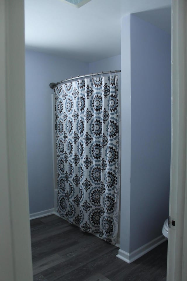 bathroom featuring toilet, wood-type flooring, and a shower with curtain