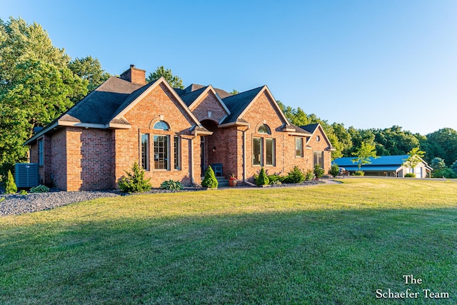 view of front of property with central AC and a front lawn